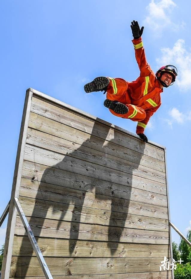 百米障碍救助训练中，消防员飞跃障碍。